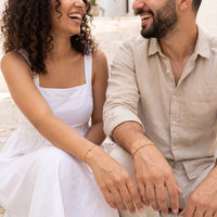 Thumbnail for Heart Bond Matching Bracelet Set in Gold — worn by a couple sitting on sunlit stone steps