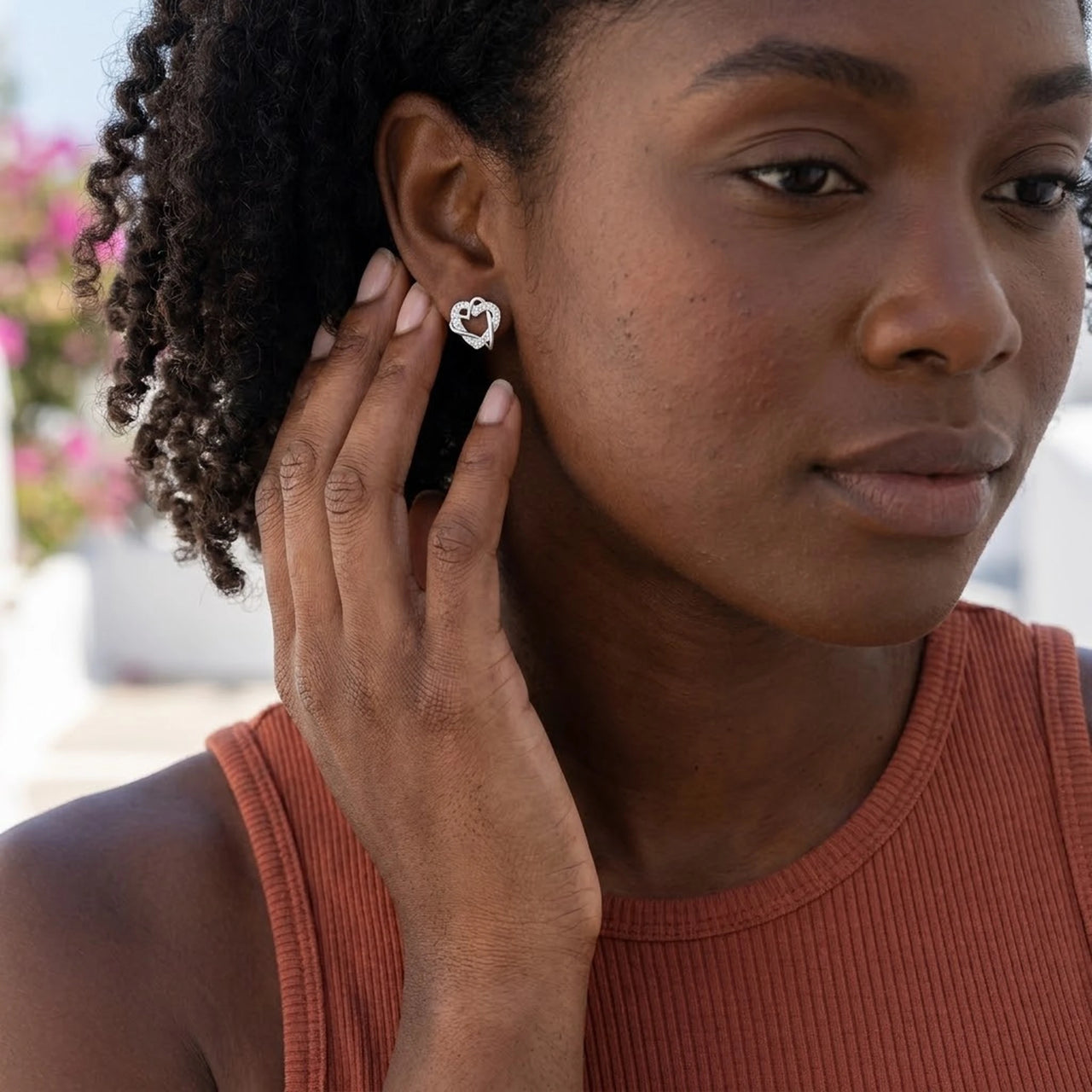 Woman gently touching her silver stud earrings | SKU: 4478648-platinum-plated-clear