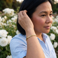 Thumbnail for Woman gently touching her Love Yourself More And Better bracelet in gold | SKU: lymab-g