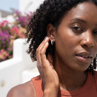 Thumbnail for Woman gently touching her silver huggie hoop earrings | SKU: 22023999-rhodium