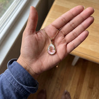 Thumbnail for The gold teardrop photo pendant in an open palm by a window, showing its real small size | SKU: TPH-DRPN-GOLD