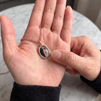 Thumbnail for Thumb warming the rose gold oval pendant: the hidden photo appears under the thumb while the rest stays black | SKU: TPH-OVLN-ROSEGOLD